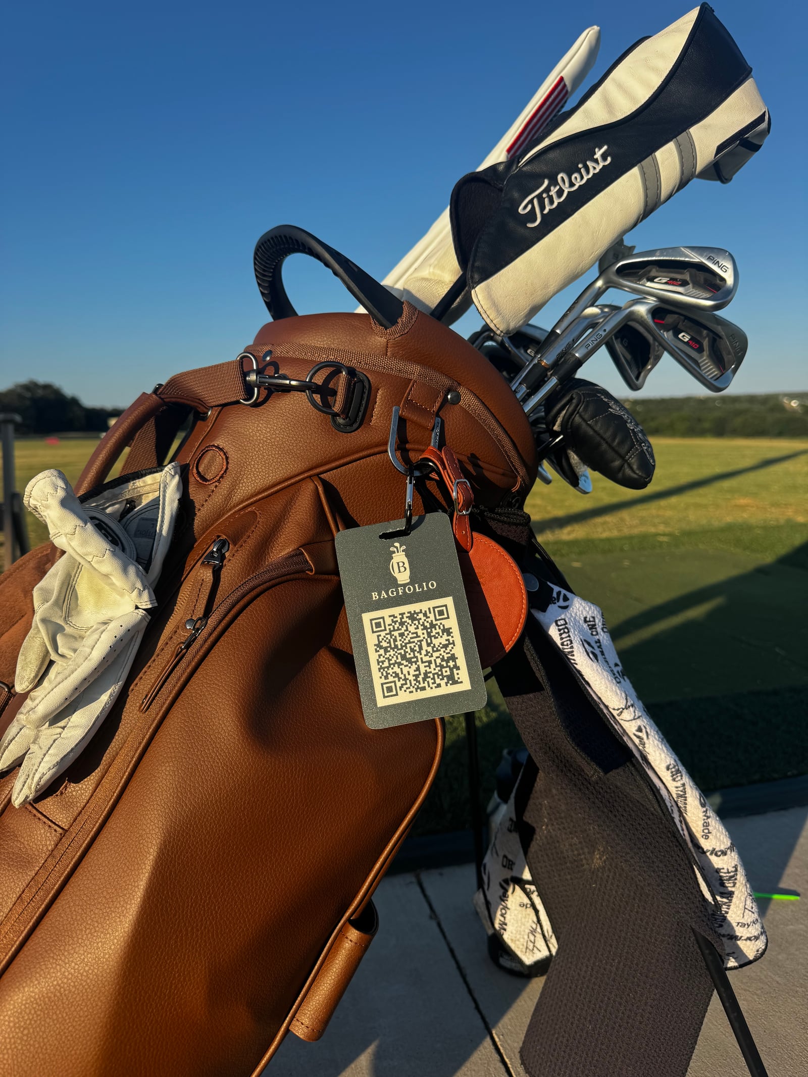 A real Bagfolio QR tag clipped to a brown golf bag at a golf course